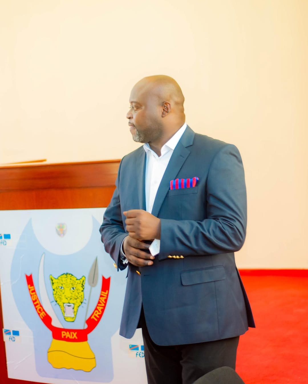 Jean-Jacques Tembele Buku aux côtés des armoiries de la RDC